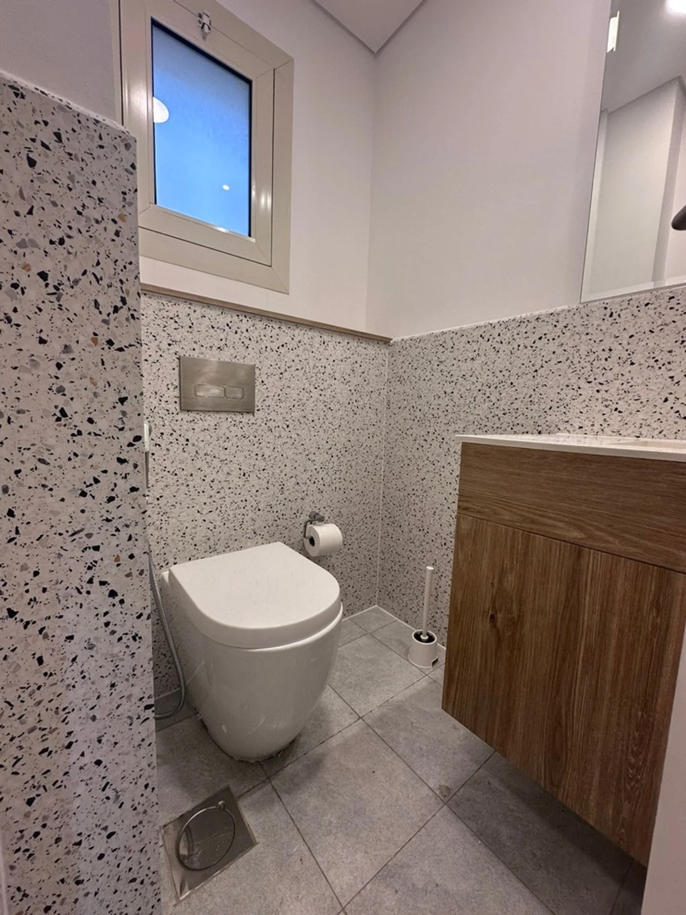 Bathroom walls wrapped in terrazzo vinyl with wood vanity Dubai