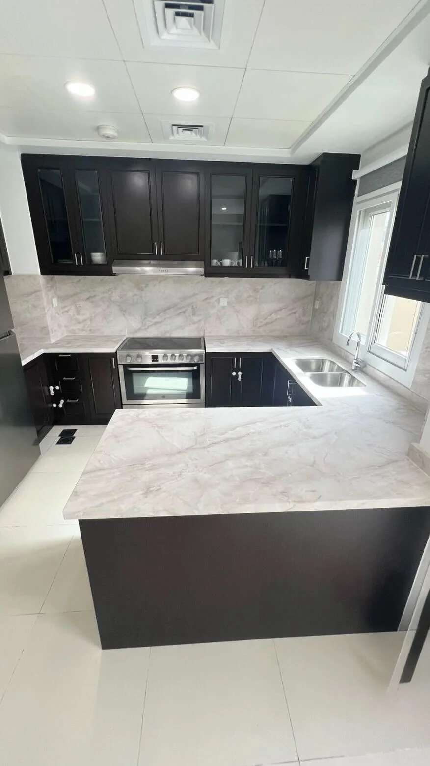 White marble countertop wrap with dark wood cabinets Dubai kitchen