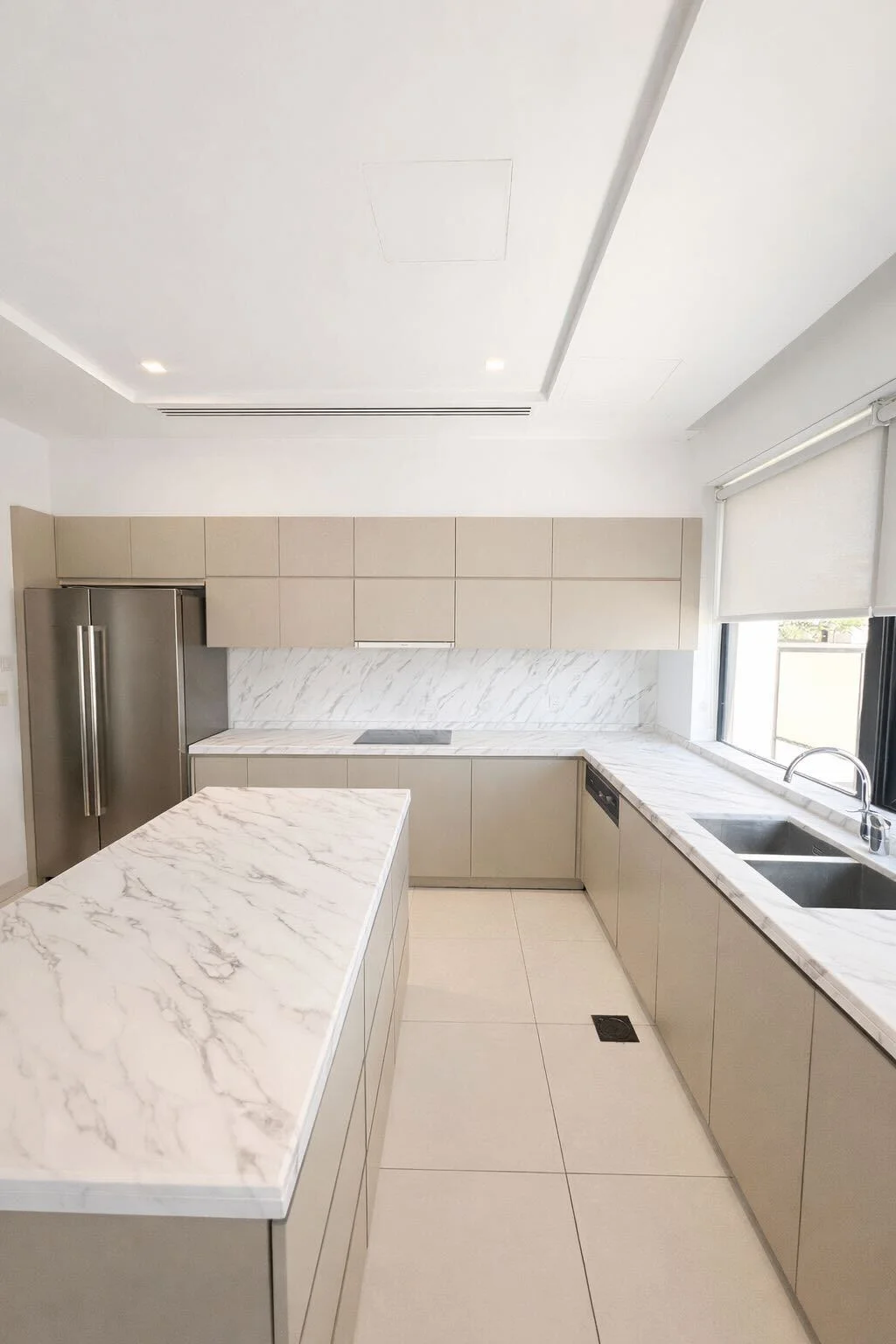White marble island countertop vinyl wrap with taupe cabinets Dubai kitchen