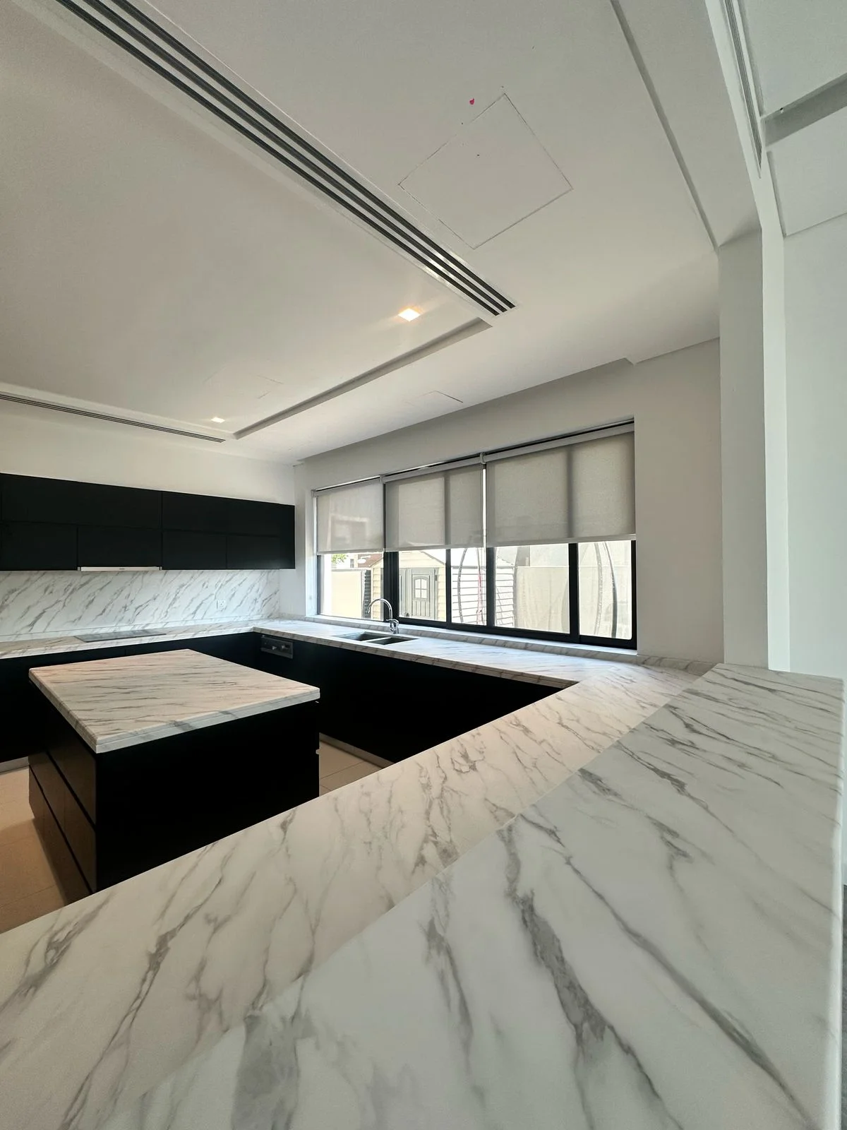 White marble island countertop vinyl wrap with black cabinets Dubai kitchen